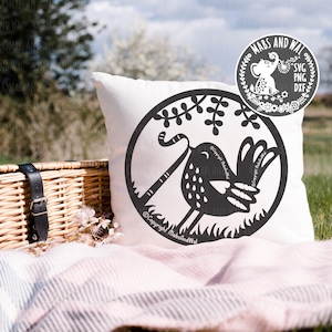 Könnte beinhalten: Ein weißes Kissen mit einer schwarz-weißen Illustration eines Vogels, der einen Stock in seinem Schnabel hält. Der Vogel ist von Blättern umgeben und der Text "Copyright MabsAndWal" steht unter dem Vogel.