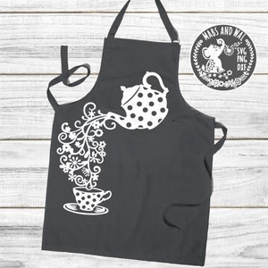 Könnte beinhalten: Eine schwarze Schürze mit einem weißen Design einer Teekanne, die Blumen in eine Teetasse gießt. Das Design ist im Punkte-Muster.