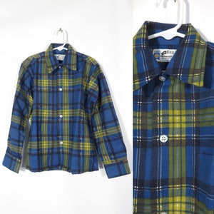 Puede incluir: Camisa de franela a cuadros azules, amarillos y negros con cuello abotonado y mangas largas. La camisa tiene un bolsillo en el lado izquierdo y una etiqueta que dice "Whichever" con un logotipo de un círculo con una estrella dentro.