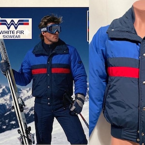 May include: A color-blocked ski jacket featuring a bright blue upper section, a dark navy lower section, and a horizontal red stripe across the chest. The jacket has a high collar, a front zipper closure with metal snaps, and a ribbed hem at the waist.