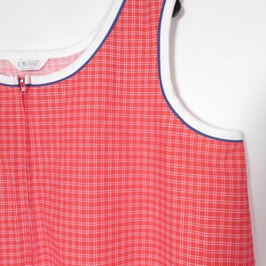 May include: A sleeveless, red and white plaid dress with a white and blue trim. The dress has a full-length zipper and the brand name "KOMAR" is visible on the label.
