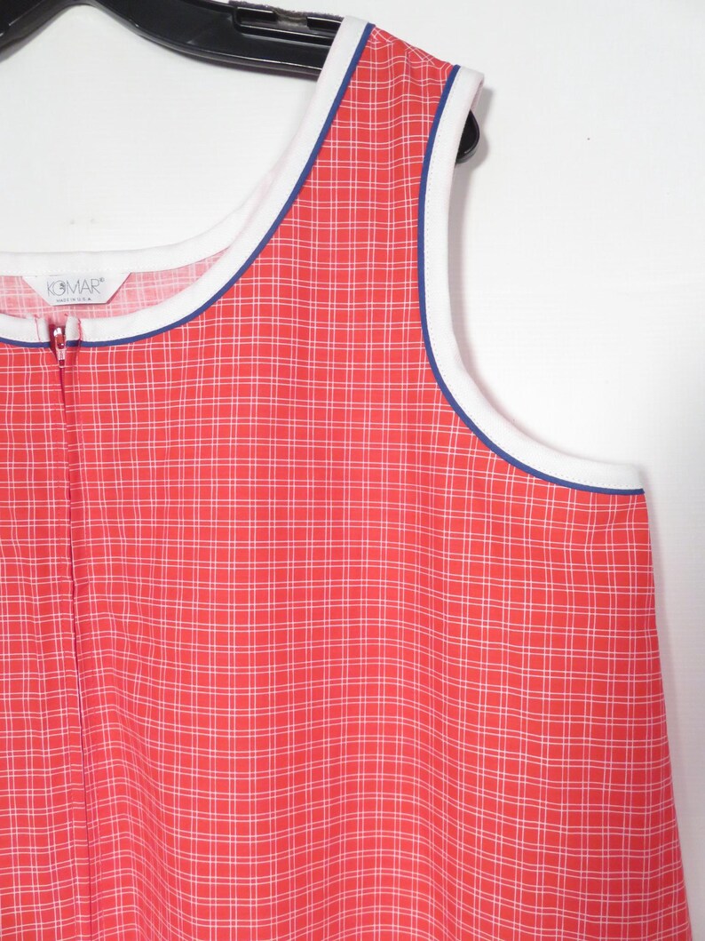 May include: A sleeveless, red and white plaid dress with a white and blue trim. The dress has a full-length zipper and the brand name "KOMAR" is visible on the label.
