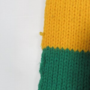 May include: A knitted scarf with yellow and green stripes. The scarf is made of a soft, textured yarn.
