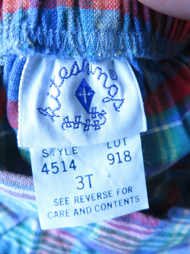 May include: White tag with blue text and a blue diamond logo. The tag reads "Style 4514 Lot 918 3T See Reverse for Care and Contents".