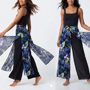 May include: Black palazzo trousers with a floral overlay in blue, purple, and green. The sheer overlay flows down the sides. The model is wearing a black vest top.