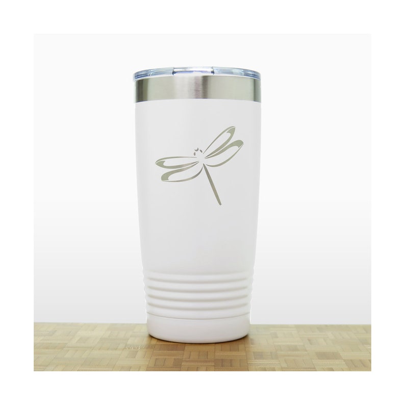 May include: White stainless steel tumbler with a laser-etched dragonfly design. The tumbler has a double-wall insulated design and a lid.