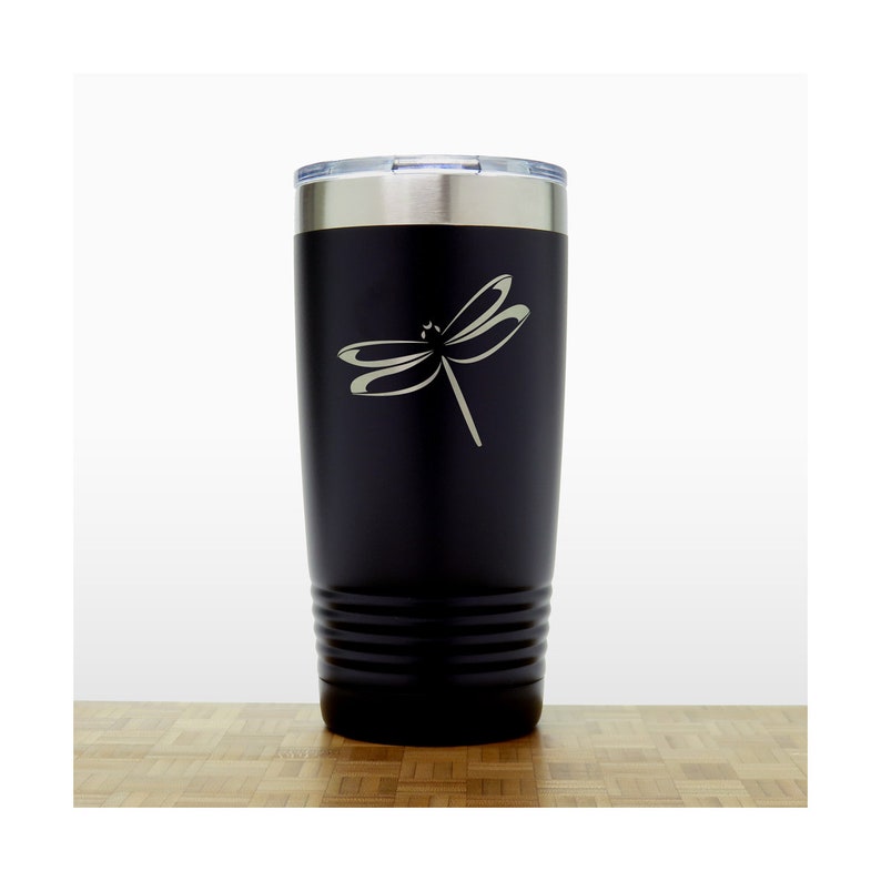 May include: Black stainless steel tumbler with a dragonfly design engraved on the side. The tumbler has a black lid and a silver band around the top.