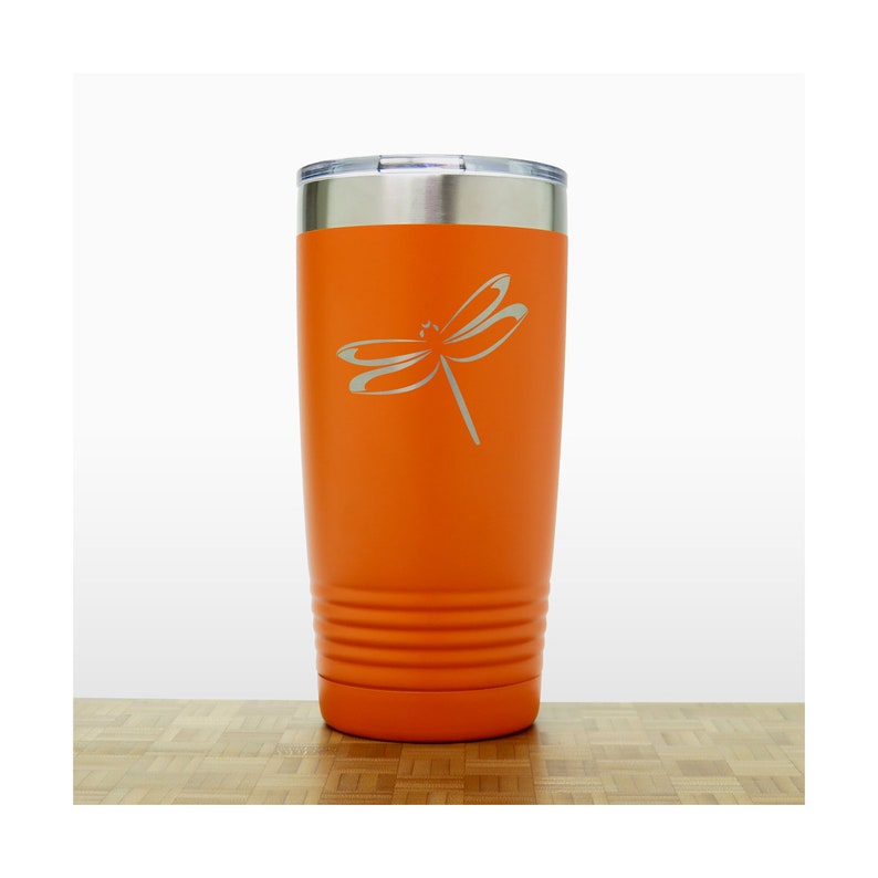 May include: Orange stainless steel tumbler with a dragonfly design engraved on the side.