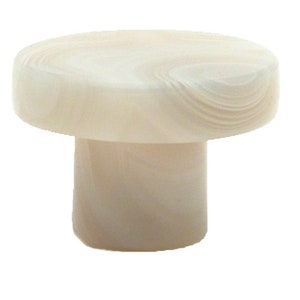 Op de afbeelding: Een witte flessenstop gemaakt van glad, gepolijst materiaal. De bovenkant van de stop is rond en heeft een licht getextureerd oppervlak. De onderkant van de stop is cilindrisch.