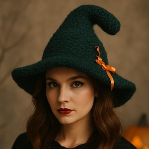 May include: A dark green witch hat with a wide brim and a pointed crown, decorated with an orange ribbon. The hat is made of a textured material. The person is wearing a black top and cape, with red lipstick.