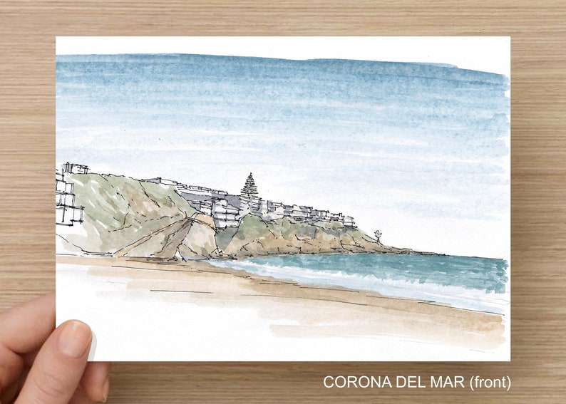 May include: Watercolor painting of a beach scene with a cliffside town in the background. The sky is a light blue, and the water is a turquoise blue. The beach is a light brown, and the cliffside is a dark brown. The town is a light brown, and the trees are a dark green. The painting is titled "CORONA DEL MAR (front)".