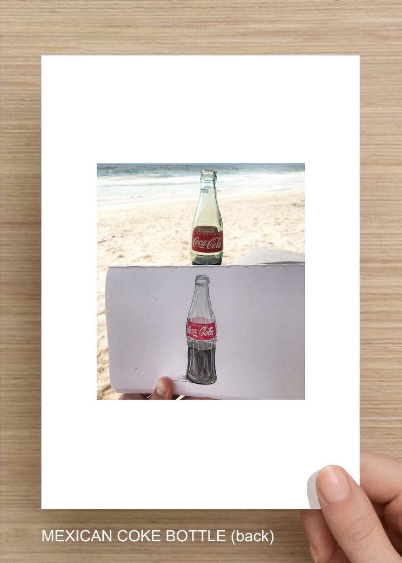 May include: A drawing of a Coca-Cola bottle on a piece of paper, with a real Coca-Cola bottle in the background.
