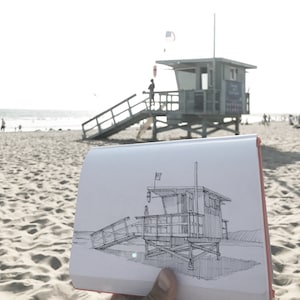 May include: A hand holds a sketch of a lifeguard stand on the beach. The sketch is in black ink on white paper. The lifeguard stand is a simple structure with a roof and a ladder. The sketch is detailed and realistic.