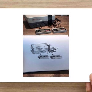 May include: An image featuring a classic Nintendo Entertainment System (NES) console with two controllers. The image also includes a sketch of the same console and controllers. The console is gray and black, with the controllers featuring red and gray buttons.