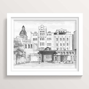 May include: A black and white ink drawing of a building with the text "Hotel Emma" on the front. The building has a large arched entrance and a series of windows. The drawing is framed in a white frame.