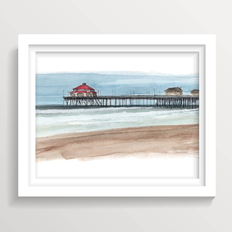 May include: Watercolor painting of a pier with a red roofed building on the end, extending over a blue ocean with white waves and a sandy beach.