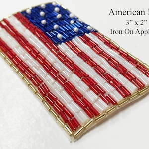 May include: A 3" x 2" iron-on applique of the American flag. The flag is made of red, white, and blue beads and has a gold border.