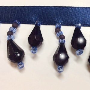 May include: A navy blue ribbon trim with black faceted teardrop beads and blue glass beads.