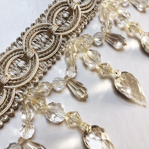 May include: Gold trim with a beaded fringe of clear faceted teardrop crystals.