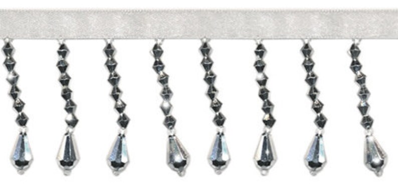May include: Silver beaded fringe trim with teardrop-shaped beads. The fringe is attached to a white ribbon.