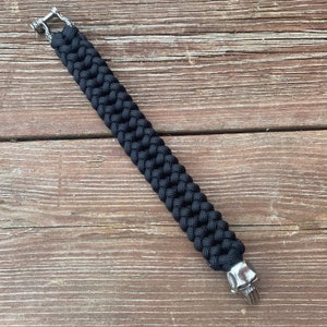 May include: A black paracord bracelet with silver skull and hook clasps.