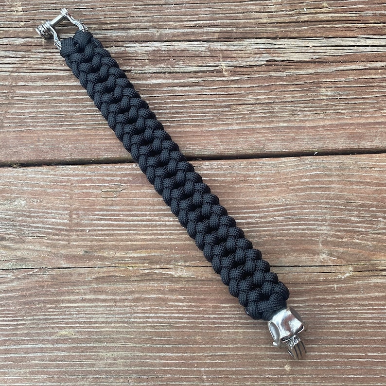 May include: A black paracord bracelet with silver skull and hook clasps.