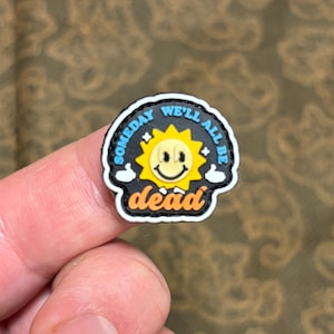 Könnte beinhalten: Ein schwarzer und weißer Patch mit einer gelben Smiley-Sonne und dem Text "Someday we'll all be dead" in einem blauen und weißen Kreis.