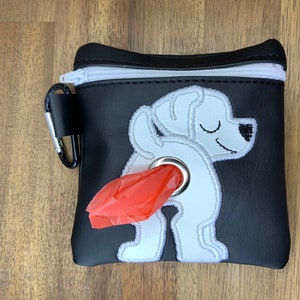 May include: Black leather dog poop bag holder with a white embroidered dog design and a red poop bag dispenser.