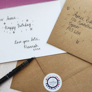 May include: A white card with black handwritten text that says "Dear Aimee, Happy Birthday. Love you lots, Hannah XXXX". The card is on top of a brown envelope with a white sticker that says "Miss Respoke Papercuts". The envelope has black handwritten text that says "Aimee Rich, 106 Kimbolton, Copnor, P03 60A".