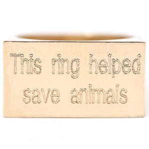 May include: A gold ring with a rectangular band that says "This ring helped save animals".