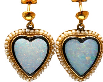 May include: A pair of gold heart-shaped earrings with opal stones set in black enamel. The earrings are surrounded by a border of small pearls.