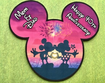 Könnte beinhalten: Ein pinkfarbenes und violettes Design in Form einer Mickey Mouse mit einer Silhouette von Mickey und Minnie Mouse, die sich vor einem Feuerwerk küssen. Der Text "Mom & Dad" befindet sich auf dem linken Ohr und "Happy 40th Anniversary" auf dem rechten Ohr.