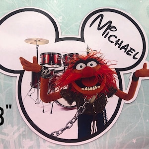 May include: A die-cut image of Animal from The Muppets, in a Mickey Mouse ear shape. Animal is in front of a drum set, with the text "Mr. Michael" above him. The image is 8 inches in height.
