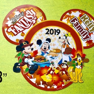 May include: A red, white, and brown Mickey Mouse-shaped ornament with a Thanksgiving theme. It features Mickey Mouse, Minnie Mouse, Donald Duck, and Goofy dressed in pilgrim costumes. The ornament says "Disney Fantasy" and "Kelly Family" and "2019".