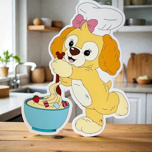 May include: A cartoon cutout of a yellow dog wearing a chef's hat and pink bow, holding a wooden spoon over a blue bowl filled with dessert. The dog is smiling. The bowl contains a swirl of cream, a strawberry, and candy.