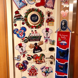 Pu&ograve; includere: Una porta bianca decorata con addobbi natalizi a tema Disney, con personaggi come Topolino e Minnie. Sono presenti anche una ghirlanda e un organizer sospeso rosso e blu.