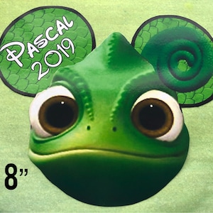 May include: A green Pascal the chameleon character cutout with brown eyes and the text "PASCAL 2019". The cutout is 8 inches in height.