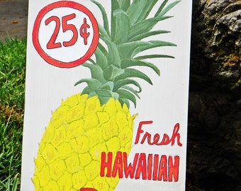 May include: A white sign with red and white text advertising fresh Hawaiian pineapple for 25 cents. The sign features a hand-painted illustration of a pineapple with green leaves.