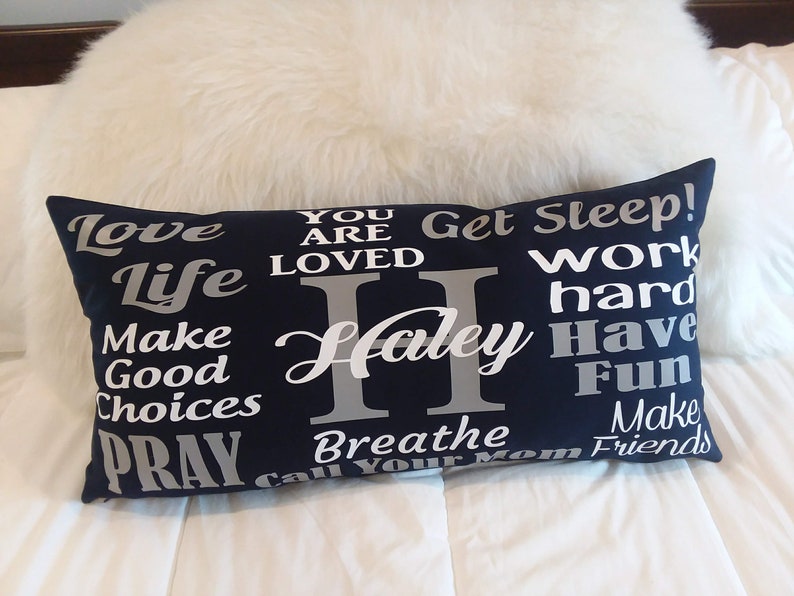 May include: A navy blue pillow with white and silver text. The text reads "Love Life Make Good Choices Pray Breathe Call Your Mom Get Sleep! Work Hard Have Fun Make Friends" with the name "Haley" in the center.