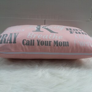 May include: Pink pillow with a zipper closure and white text that reads "Pray", "Breathe", "Call Your Mom", "Have Fun", "Make Friends", and "Seriously".