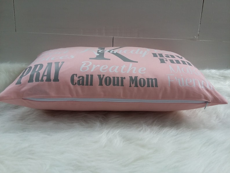 May include: Pink pillow with a zipper closure and white text that reads "Pray", "Breathe", "Call Your Mom", "Have Fun", "Make Friends", and "Seriously".
