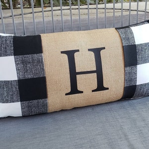 May include: A black and white buffalo plaid pillow with a burlap center panel featuring a large black letter "H".
