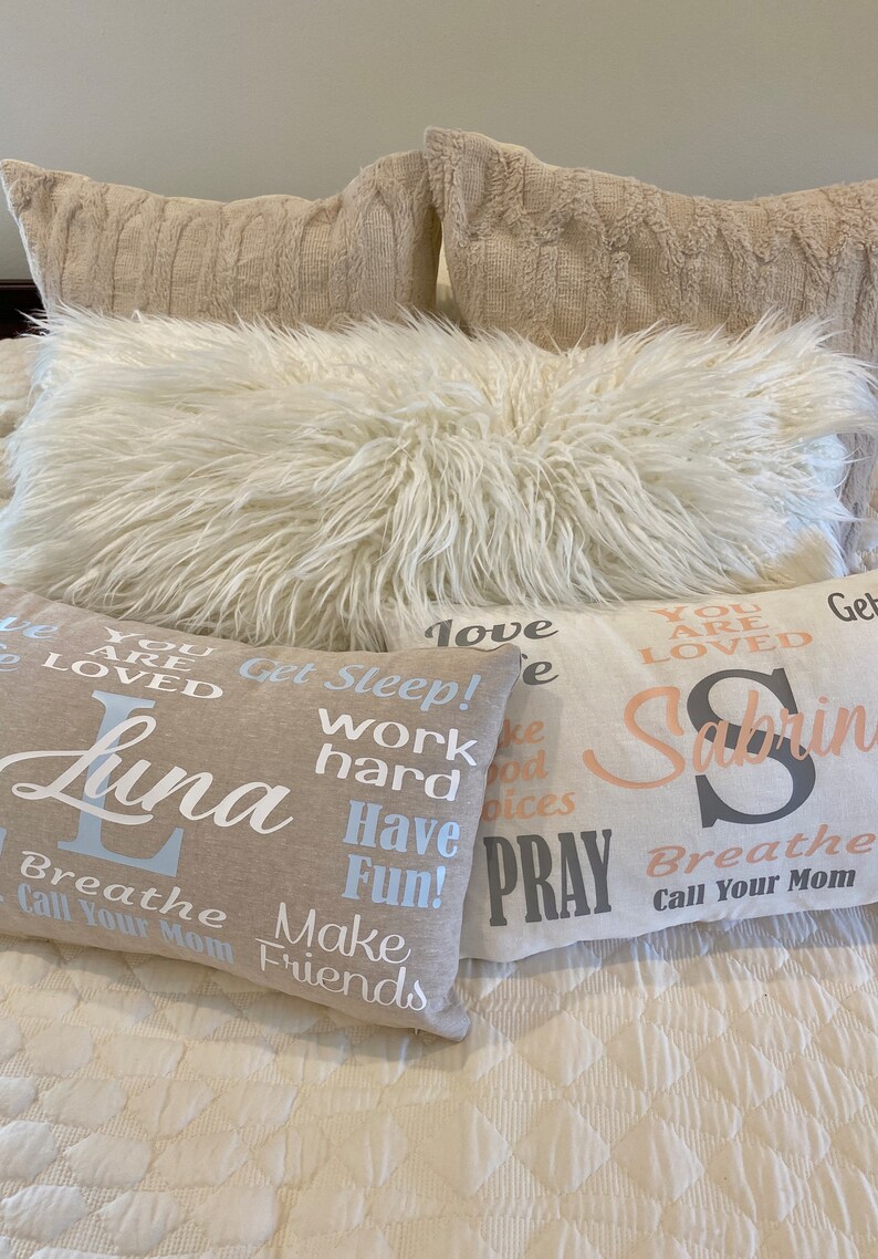 May include: Four decorative throw pillows with inspirational text. The pillows are beige and white with black and blue lettering. The text on the pillows reads: "You are loved", "Get Sleep! Work hard Have Fun! Make Friends", "Love", and "You are loved Sabrina Breathe Call Your Mom".