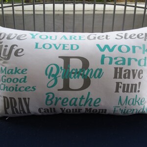 May include: White pillow with gray and teal text. The text says "Love You Are Get Sleep! Life Loved Work Hard Brianna Have Fun! Make Good Choices Pray Breathe Call Your Mom Make Friends".