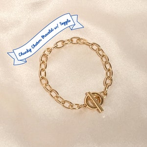 May include: Gold chunky chain bracelet with a toggle clasp.  "Chunky Charm Bracelet w/ Toggle" is written on a blue banner.
