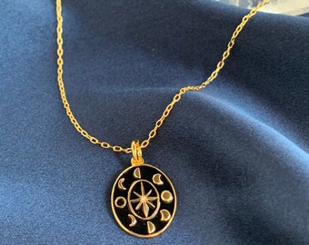 May include: Gold chain necklace with a black enamel pendant featuring a star and moon phases.