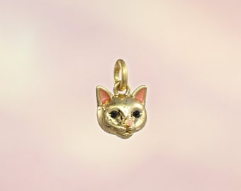 May include: Gold charm of a cat's face with pink ears and black eyes.