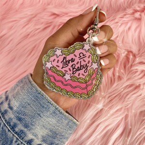May include: Pink and gold glitter heart-shaped keychain with the text "Libra Baby" and the Libra zodiac symbol.