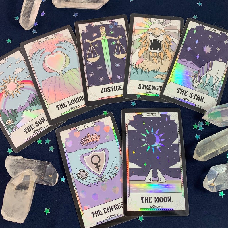 May include: A set of ten tarot cards with holographic foil accents. The cards feature illustrations of the Sun, The Lover, Justice, Strength, The Star, The Empress, The Moon, and other tarot card symbols.