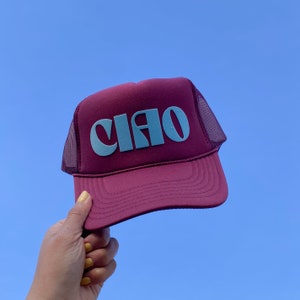 May include: A burgundy trucker hat with a blue "CIAO" graphic on the front.